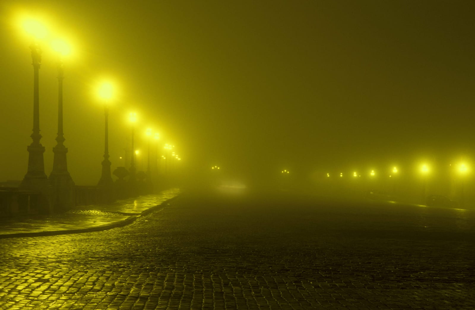 Une avenue rectiligne bordée de réverbères, la perspective se perdant dans une brume dorée