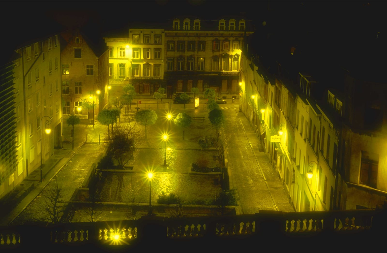 Un ensemble de bâtiments en terrasses éclairés de jaune, vus de haut dans la nuit